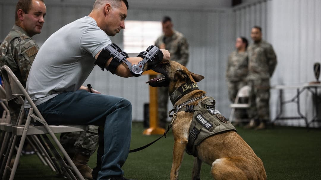 Master Sgt. Adam Macowicz comforting Military Working Dog Rita during her retirement ceremony at Edwards AFB.