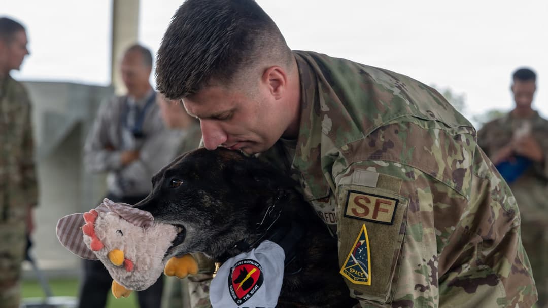Staff Sgt. Trey Nelson hugging Military Working Dog Ringo B393 during his retirement at Vandenberg Space Force Base.