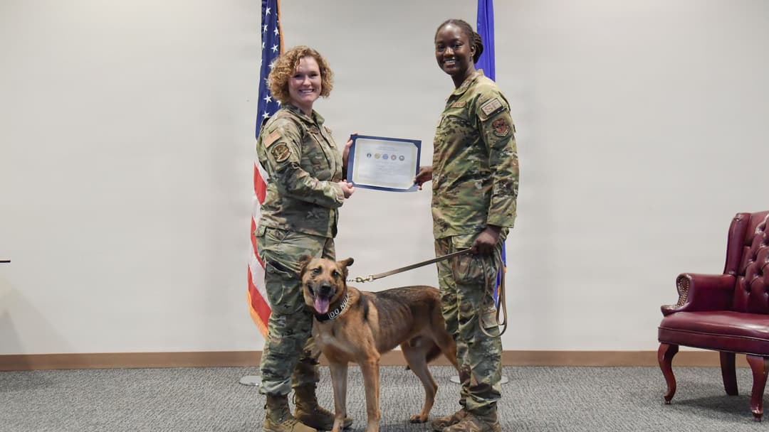 Maj. Katie Thalhamer presenting Sgt. Sydney Waiters with a retirement certificate for MWD Durango at Keesler AFB.