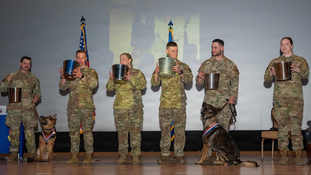 354th Security Forces Squadron handlers raising water buckets in a toast during a K-9 retirement ceremony in Alaska.